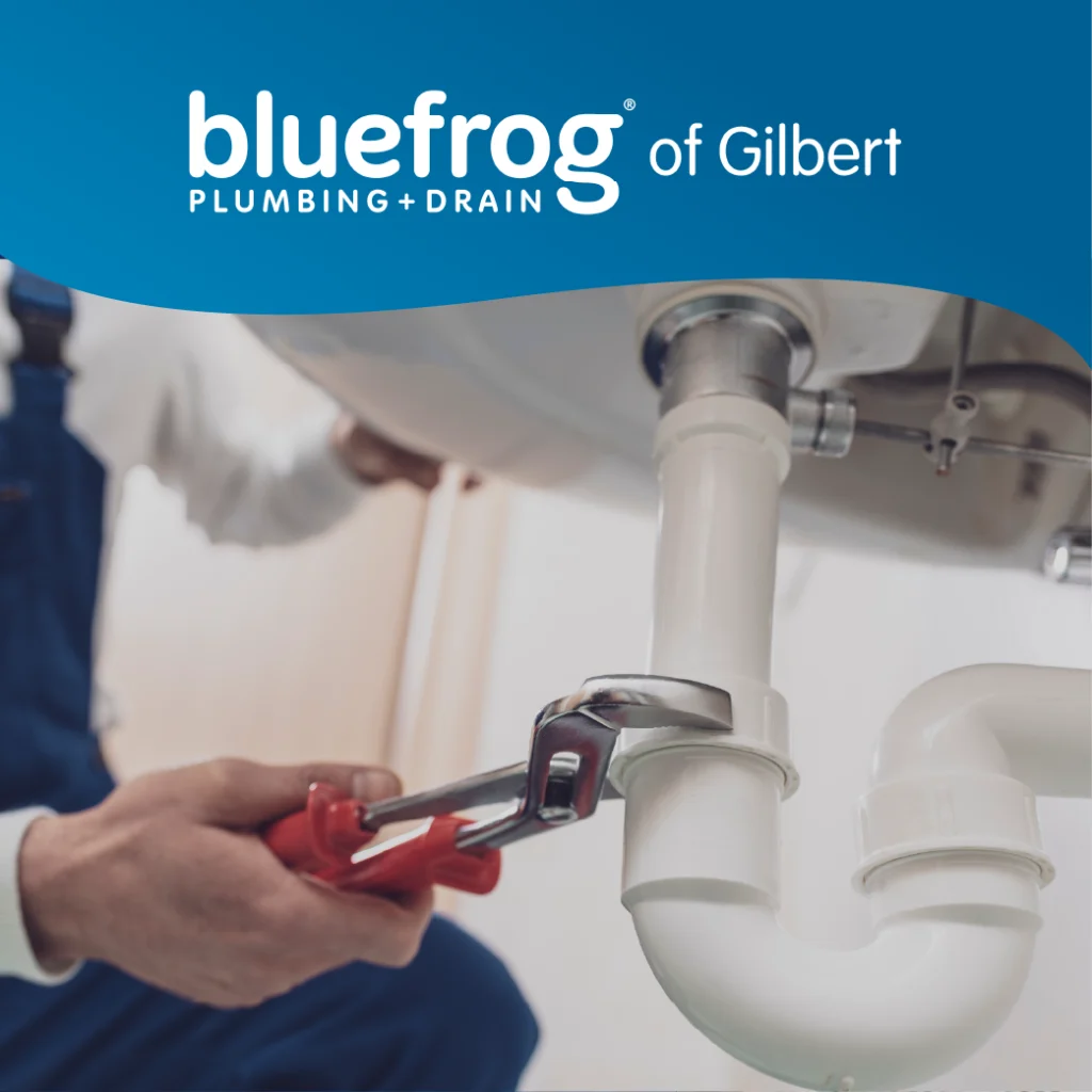 Plumber using a red wrench to secure PVC piping under a bathroom or kitchen sink